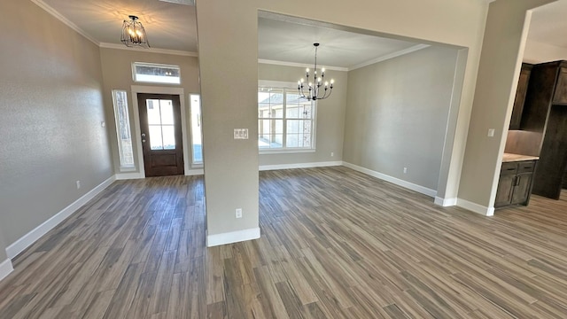 foyer entrance with hardwood / wood-style flooring, ornamental molding, and an inviting chandelier