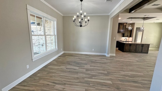 unfurnished dining area featuring wood-type flooring, crown molding, and sink