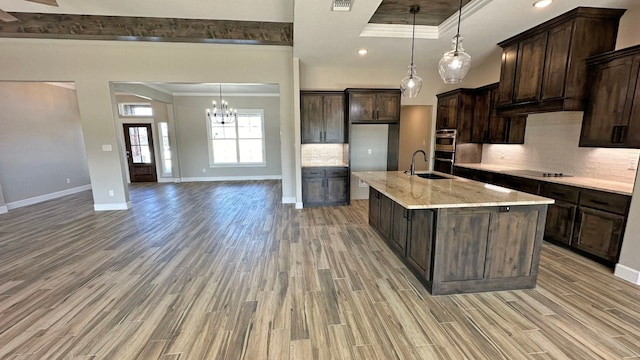 kitchen featuring light stone countertops, sink, backsplash, light wood-type flooring, and ornamental molding