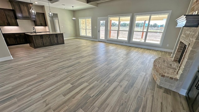 unfurnished living room with sink, a fireplace, and light wood-type flooring