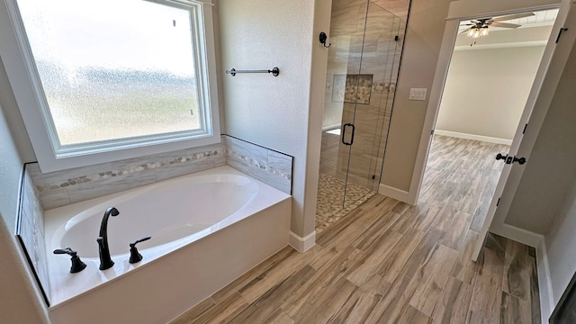 bathroom featuring ceiling fan, plus walk in shower, and hardwood / wood-style flooring