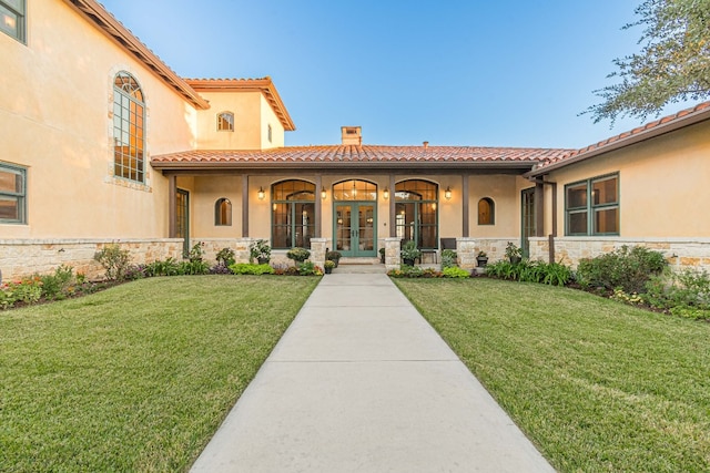 mediterranean / spanish-style house with a front lawn and french doors