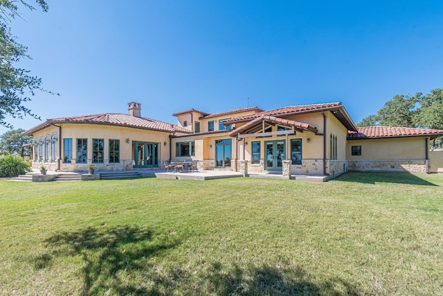 rear view of house with a lawn, a patio area, and french doors