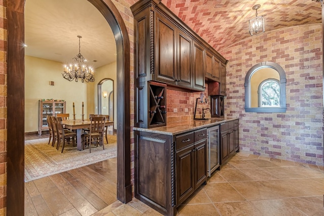 kitchen with dark stone counters, dark brown cabinets, pendant lighting, light hardwood / wood-style flooring, and wine cooler