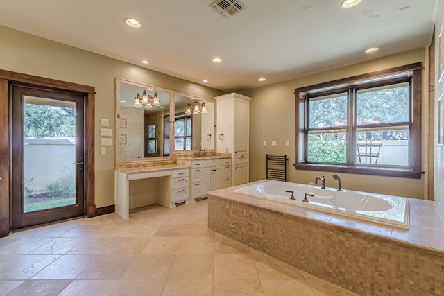 bathroom with a notable chandelier, a relaxing tiled tub, and vanity