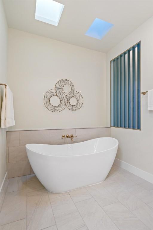 2606 Cavileer Ave, Austin, TX 78757 - full bathroom featuring a skylight, a freestanding bath, tile walls, and tile patterned floors