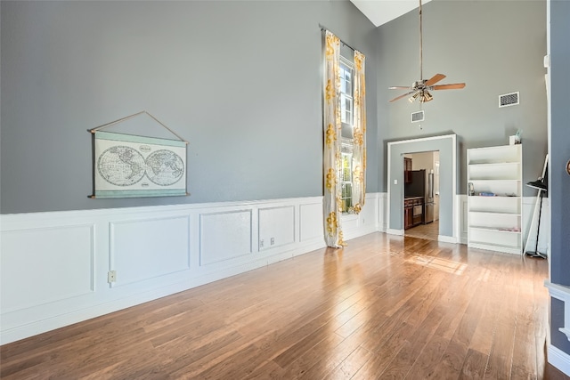 interior space featuring hardwood / wood-style floors, a towering ceiling, and ceiling fan