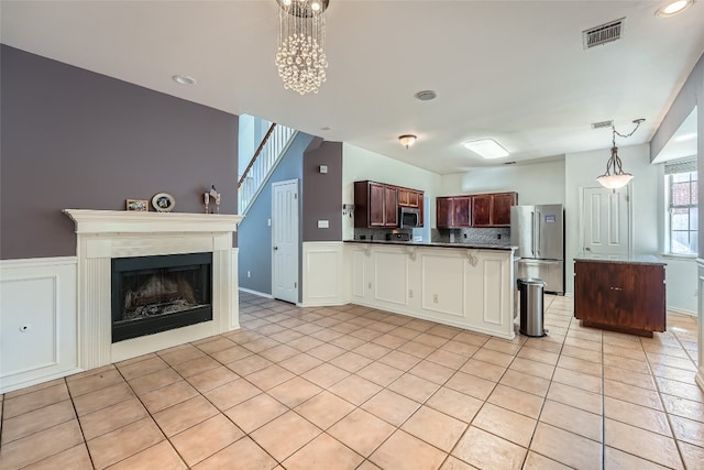 kitchen featuring dark brown cabinets, stainless steel appliances, pendant lighting, an inviting chandelier, and light tile patterned flooring