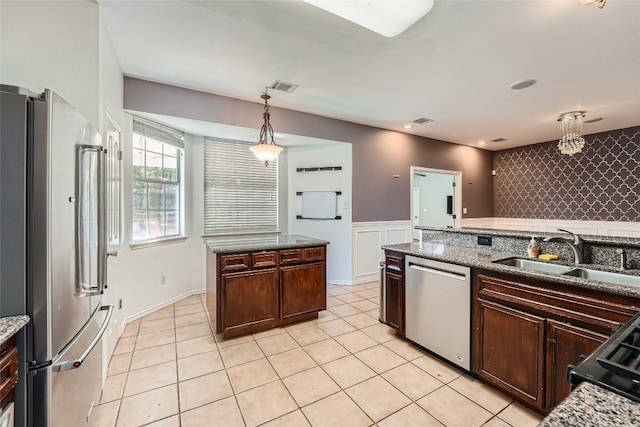 kitchen with pendant lighting, dark brown cabinetry, stainless steel appliances, and sink