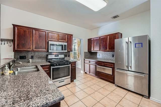 kitchen with backsplash, light tile patterned flooring, sink, and appliances with stainless steel finishes