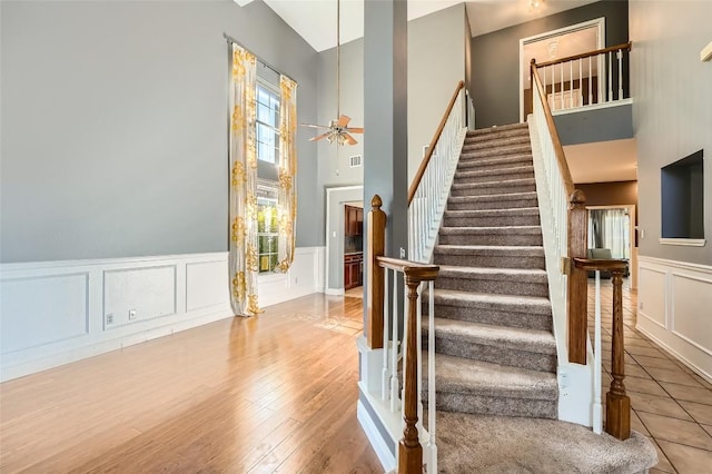 stairway featuring hardwood / wood-style flooring, ceiling fan, and a towering ceiling