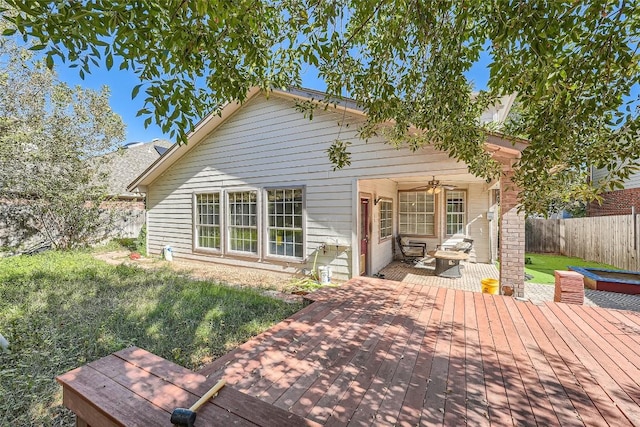 rear view of property with ceiling fan, a lawn, and a wooden deck