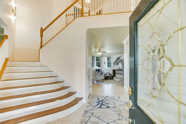 tiled entryway with ceiling fan and ornamental molding