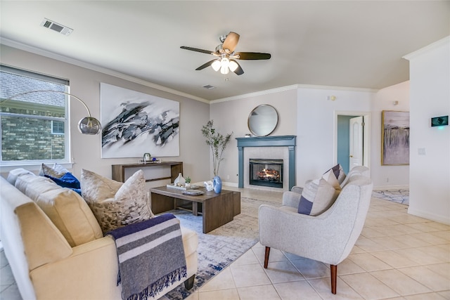 tiled living room with a fireplace, ceiling fan, and crown molding