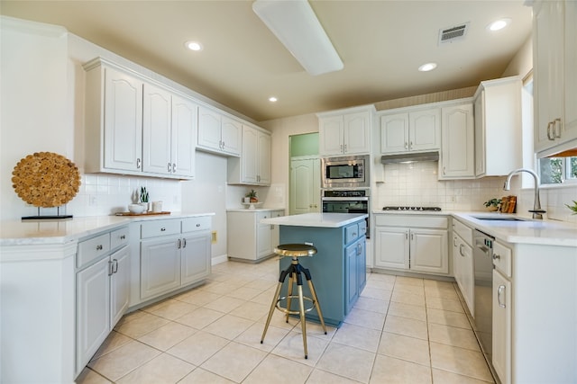 kitchen featuring a kitchen bar, stainless steel appliances, sink, a center island, and white cabinetry