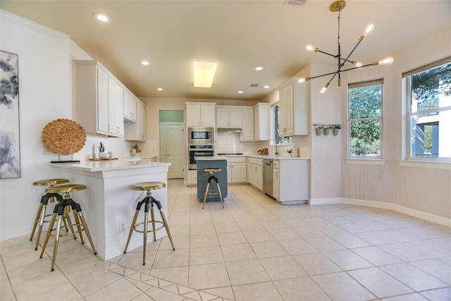 kitchen with white cabinets, a kitchen breakfast bar, appliances with stainless steel finishes, tasteful backsplash, and kitchen peninsula