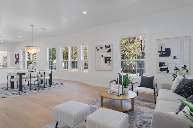 living room with wood-type flooring, a wealth of natural light, and an inviting chandelier