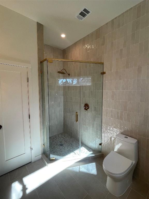 bathroom featuring an enclosed shower, tile walls, tile patterned floors, and toilet