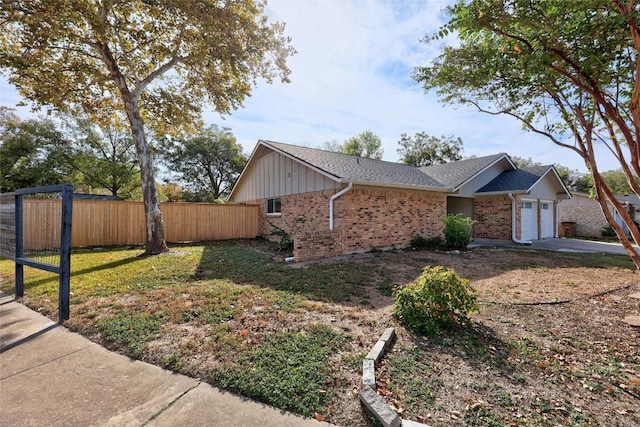 view of side of property featuring an attached garage, brick siding, fence, driveway, and roof with shingles