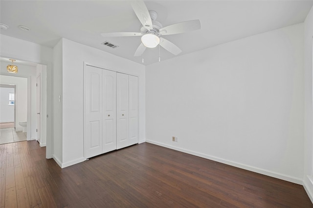 unfurnished bedroom with baseboards, visible vents, ceiling fan, dark wood-type flooring, and a closet