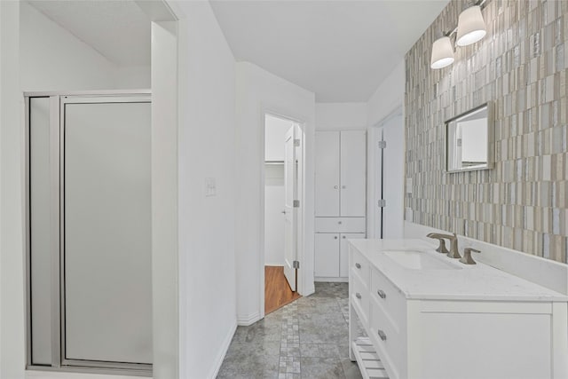 bathroom featuring a shower stall, a spacious closet, baseboards, and vanity