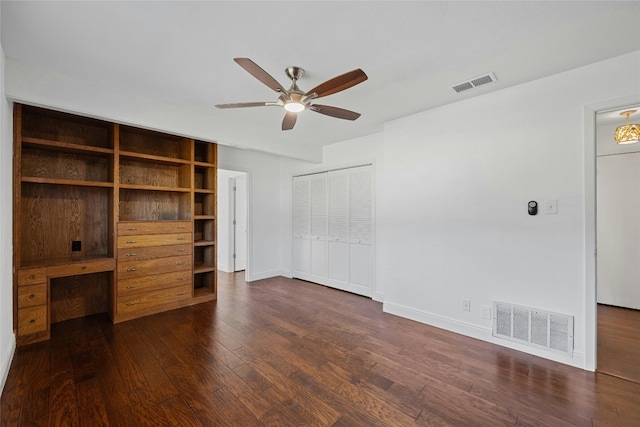 unfurnished bedroom featuring dark wood-style floors, built in study area, visible vents, and baseboards