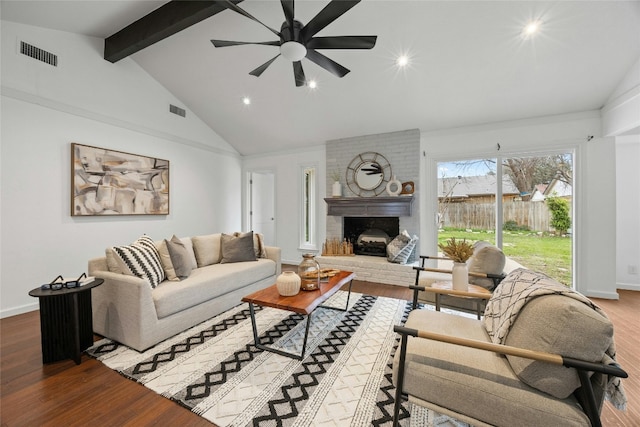 living area featuring visible vents, beamed ceiling, a fireplace, and wood finished floors