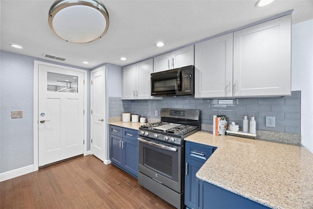 kitchen featuring stainless steel gas range, black microwave, white cabinets, and visible vents