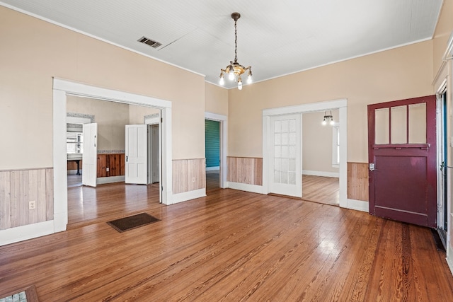 interior space with a chandelier, hardwood / wood-style flooring, crown molding, and wood walls