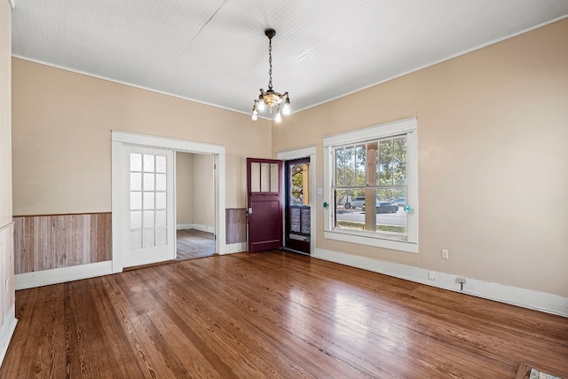 foyer entrance featuring crown molding, wooden walls, wood-type flooring, and a notable chandelier