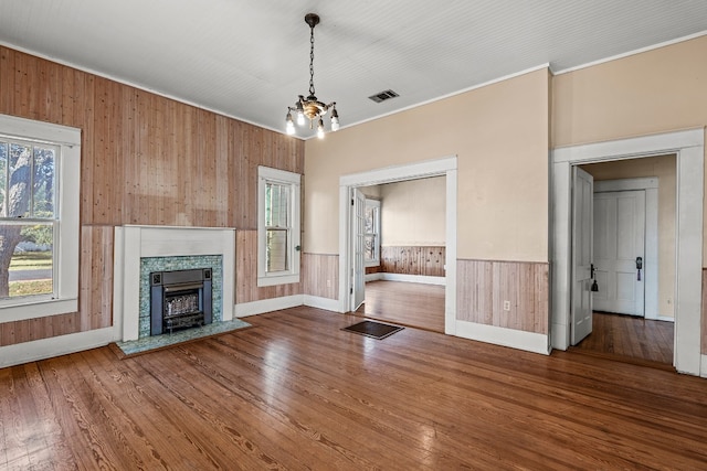 unfurnished living room with hardwood / wood-style flooring, a wealth of natural light, and wooden walls