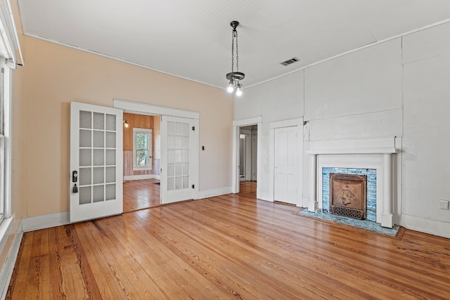 unfurnished living room featuring hardwood / wood-style floors, french doors, and ornamental molding