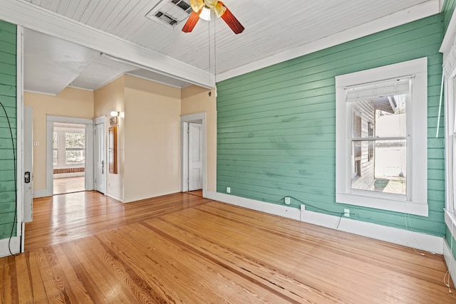 unfurnished room featuring ceiling fan, wood walls, wood-type flooring, and ornamental molding