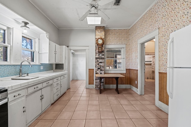 kitchen featuring tile countertops, white cabinets, white refrigerator, sink, and crown molding