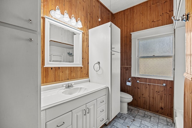 bathroom with wooden walls, vanity, and toilet