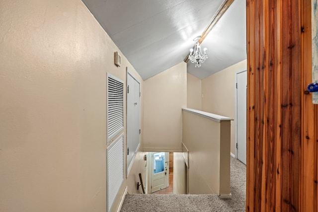 hall featuring carpet flooring, lofted ceiling, and a chandelier