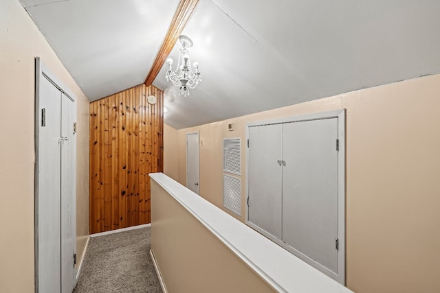 hall featuring carpet flooring, vaulted ceiling with beams, wooden walls, and a chandelier