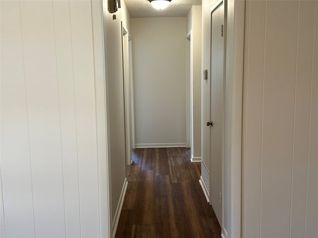 hall with a textured ceiling and dark hardwood / wood-style floors