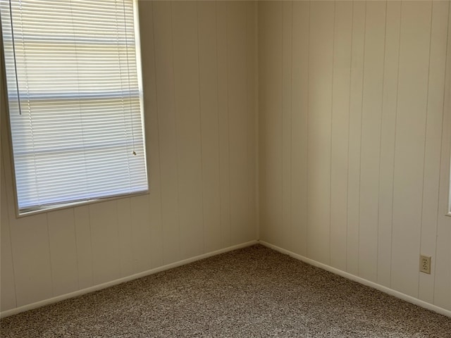 carpeted spare room featuring wooden walls