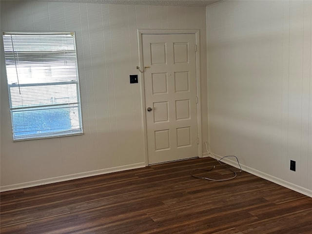 spare room featuring wood walls and dark wood-type flooring