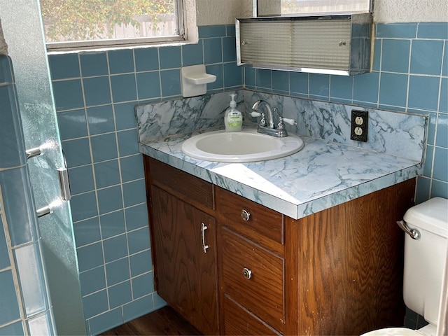 bathroom with wood-type flooring, vanity, toilet, and tile walls