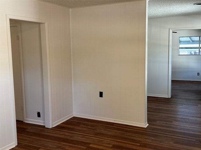 unfurnished room with a textured ceiling, dark wood-type flooring, and wood walls