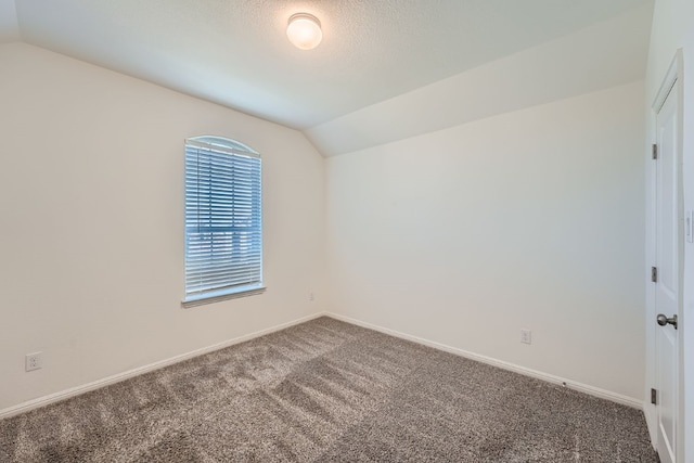 carpeted spare room with a textured ceiling and lofted ceiling