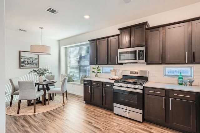 kitchen with pendant lighting, dark brown cabinetry, stainless steel appliances, and light hardwood / wood-style floors