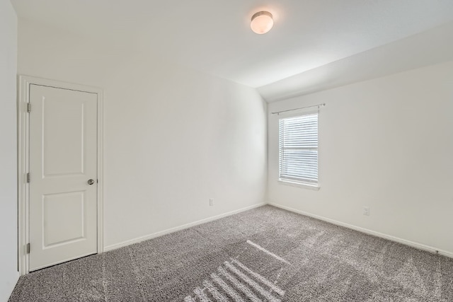 carpeted empty room with lofted ceiling