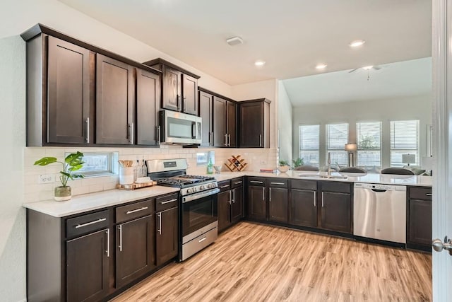 kitchen with decorative backsplash, appliances with stainless steel finishes, dark brown cabinetry, sink, and light hardwood / wood-style floors