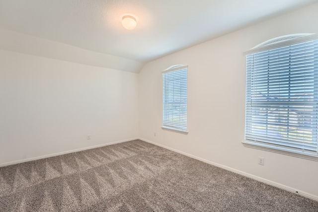 spare room featuring carpet and lofted ceiling