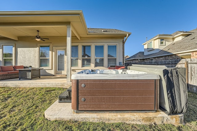 rear view of property with a hot tub, ceiling fan, and a patio area