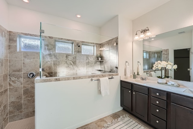 bathroom featuring tile patterned flooring, vanity, and a tile shower