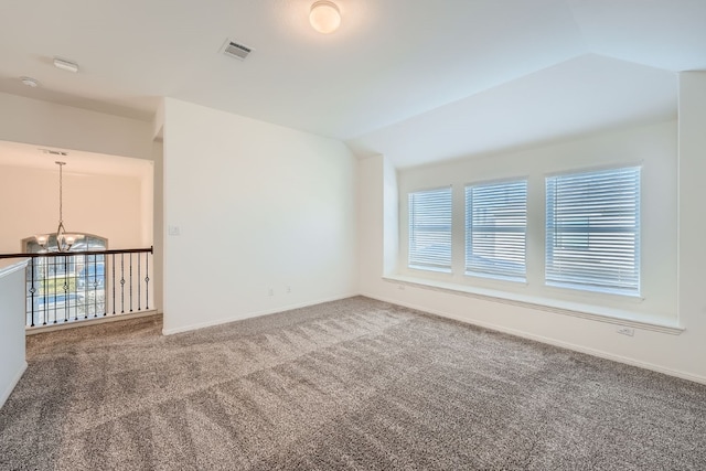 carpeted spare room with an inviting chandelier and vaulted ceiling